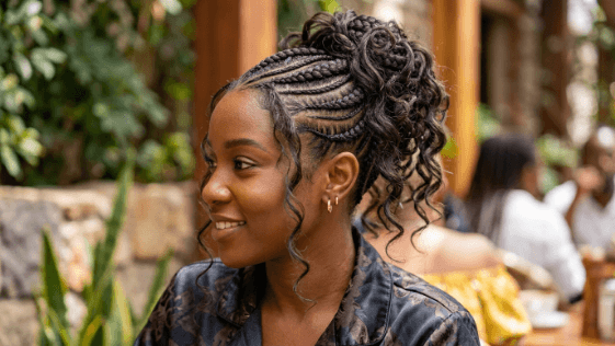 A woman with large goddess braids braided in curved lines close to the scalp, the thick raised braids swept back into a neat updo.